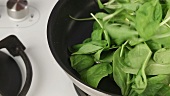 Butter being melted in a pan and spinach being fried