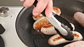 Sausages in a pan being turned