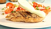 Grilled chicken breast being served with a light sauce