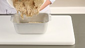 Banana bread dough being transferred to a loaf tin