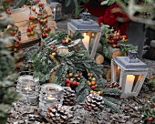 Winter arrangement with tea light holders, lanterns and pine cones