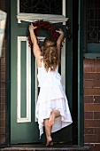 Little girl hanging a wreath on a door