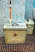 Vintage Metall Aufbewahrungsboxen im Bad vor hellblauen Wandflliesen auf dunkelbraunen Mosaikbodenfliesen