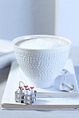 A cappuccino with a mini milk bottle basket
