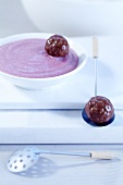 A bowl of raspberry creme with round chocolate pralines