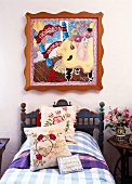 Modern Pop Art painting above a rustic country bed with floral pillows and a plaid bedspread