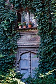 Ivy covered facade of a traditional country home with decoratively carved windows