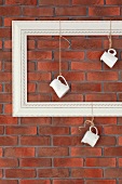 Milk jugs hanging from empty picture frame against brick wall