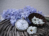 Vintage Taschenuhr und Blütenblätter auf Rattangeflecht