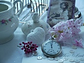 Taschenuhr vor Hyazinthenblüten und Porzellangefässe mit antikem Foto