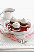 Mini meringue sandwiches filled with chocolate in raspberry sauce