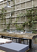Table made of rustic planks in front of climbers on wooden trellis in courtyard