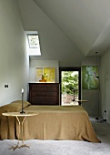 Double bed, two gilt Meret Oppenheim Traccia tables and chest of drawers in bedroom