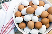 Large Bowl Full of Brown and White Eggs; Tea Towel; From Above