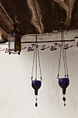 Blue glass tealight holders and lantern hanging from wooden ceiling beams