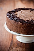 A chocolate cream cake on a cake stand