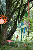 Wire chair hung from tree with colourful ribbons