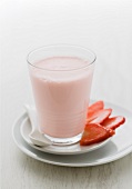 A glass of strawberry milkshake and fresh strawberries