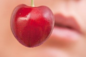 A sweet cherry in front of a face