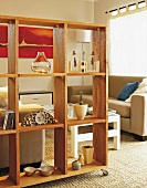 Movable shelving made of natural wood as partition in front of classic lounge area