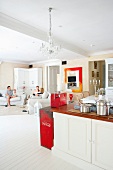 Open-plan, country house kitchen in modern interior with guests seated in lounge area