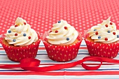 Three decorative cupcakes with a red ribbon