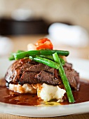 A Serving of Roast Beef Over Mashed Potatoes with Green Beans and Veal Gravy