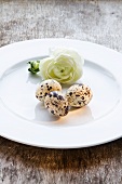 Three quails eggs and white peony on a plate