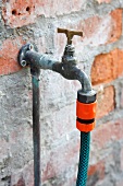 A garden hose attached to a tap on a house wall