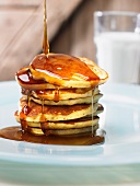 Maple syrup being drizzled over a stack of pancakes