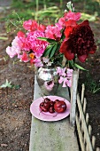 Blumenstrauss in silberner Vase und Obstteller auf rustikaler Holzbank