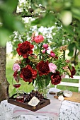 Flamboyant summer bouquet, tray and carafe of wine on garden table