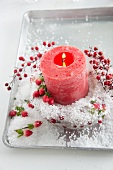 Red candle in ice bowl with St. John's wort berries, Skimmia japonica berries and artificial snow