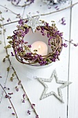 Lit candle in dish decorated with wreath of callicarpa berries and Christmas star