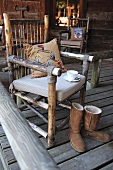 Home-made chair with cushioned seat and winter boots on wooden veranda
