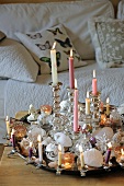 Festively decorated tray on coffee table with lit candles and Christmas baubles