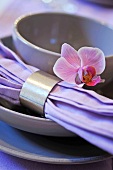 Place setting with a cloth napkin and silver napkin ring decorated with a violet flower