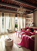 Elegantes Wohnzimmer mit rosa Polstersofa vor Fensterfront mit bodenlangen Vorhängen