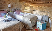 Zwei Betten auf gemütlicher Schlafgalerie mit niedriger Holzbalkendecke und heller Natursteinwand