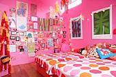 Mädchenzimmer mit rosa Wänden, zwei Betten, bunter Wanddekoration und Lichterkette