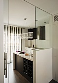 Blick durch offene Tür in eine schwarz-weiße Designerküche mit Hängelampe und Glasperlenschmucks