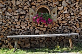 Stacked firewood with bench and decorative petunias