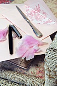 Brief, Rosenblütenblätter, Füllfederhalter und Brieföffner auf einem Stuhl