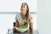 Teen girl eating salad, laughing with head back