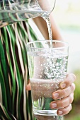 Frau giesst Wasser in ein Glas