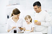 Parents and young daughter preparing breakfast in kitchen