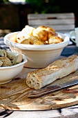 Baguette und Schüssel mit Croissants auf Holzbrett