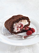 A slice of chocolate Swiss roll with a raspberry cream filling