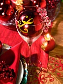 A place setting and a wine glass with red Christmas decorations