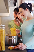 Junges Paar in der Küche kocht Spaghetti und trinkt Rotwein